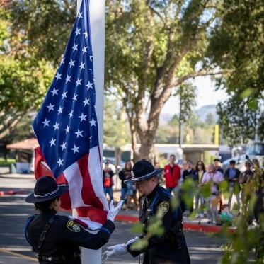 Honor Guard raising flag while crowd looks on